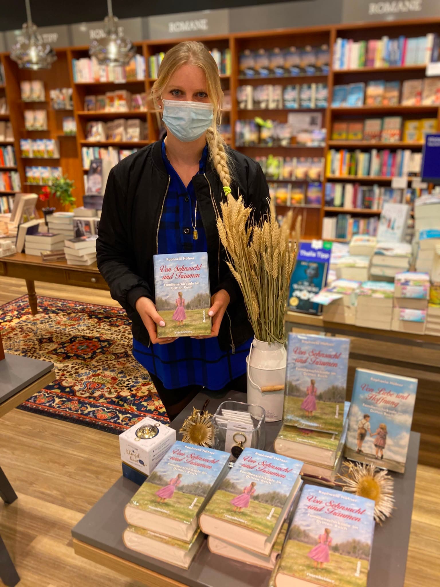 Raphaela Höfner an einem Büchertisch mit „Von Sehnsucht und Träumen“ in einer Buchhandlung