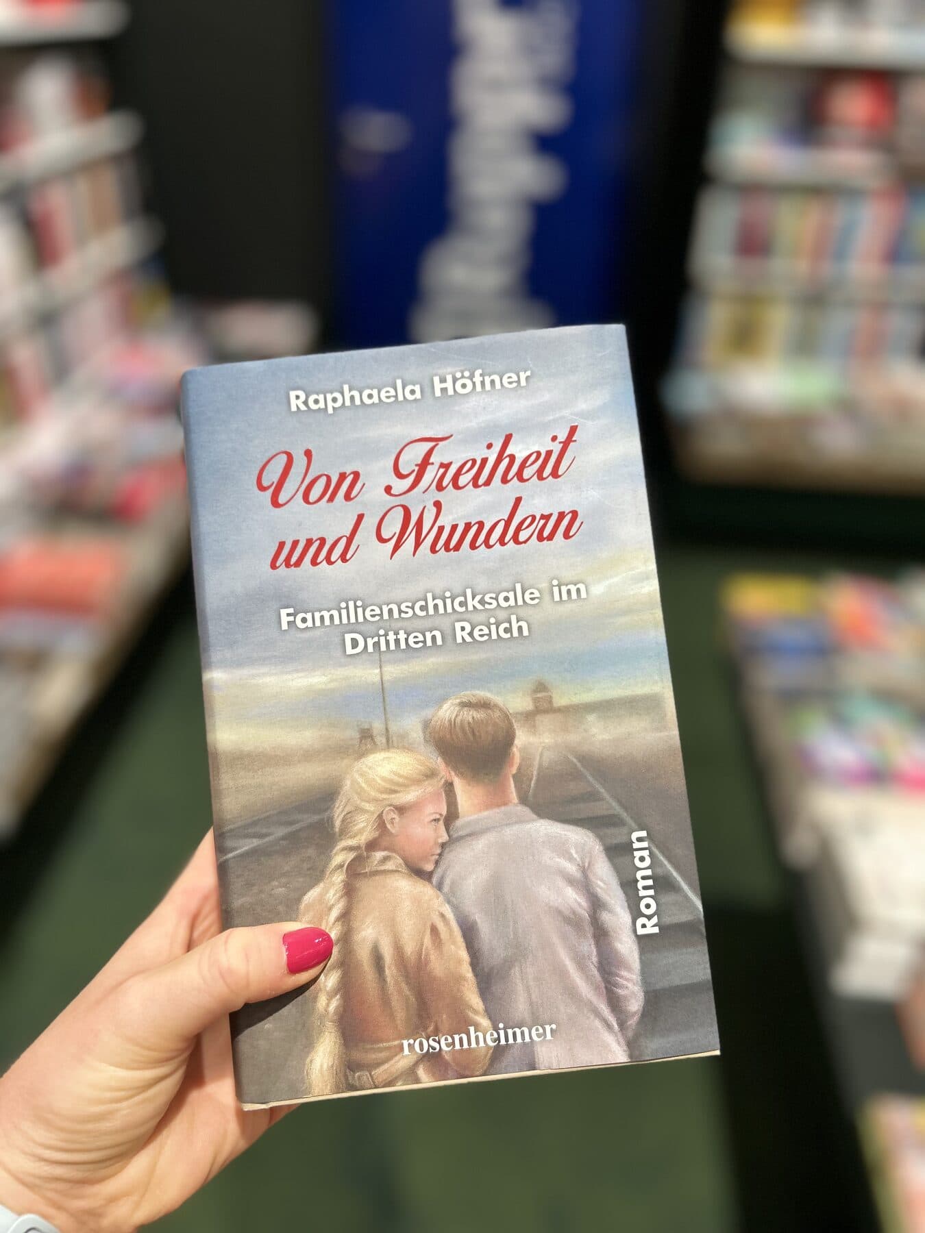 Raphaela Höfner vor einer Wand mit hunderten Familienfotografien in der Gedenkstätte Auschwitz