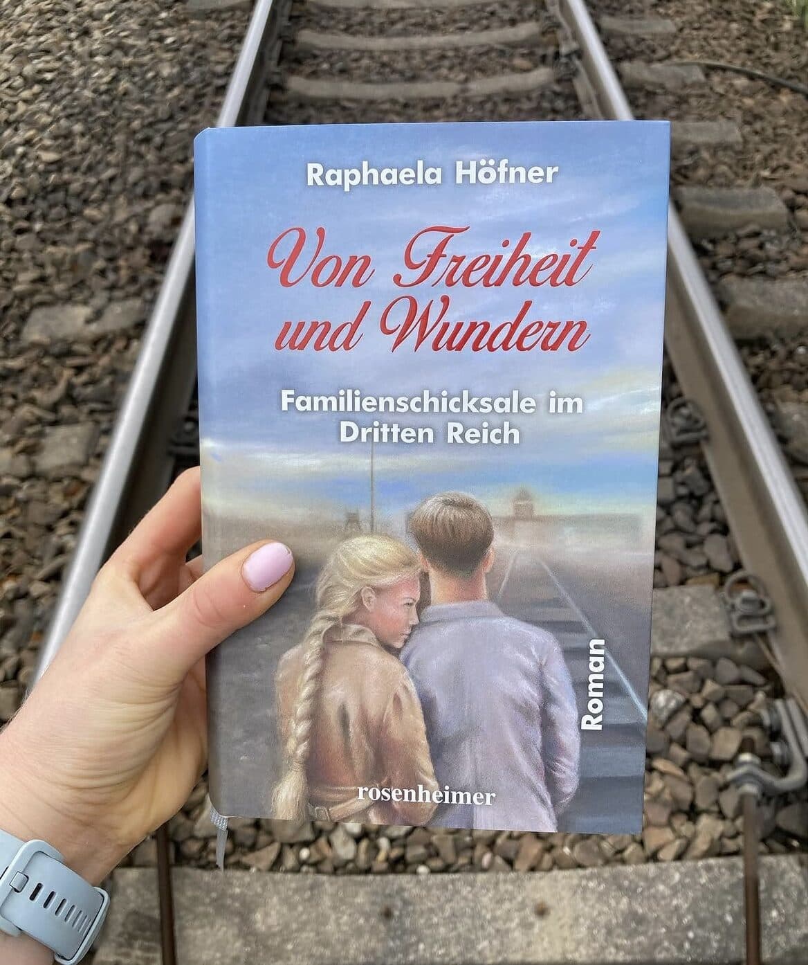 Der dritte Band „Von Freiheit und Wundern“ über einem Bahngleis gehalten