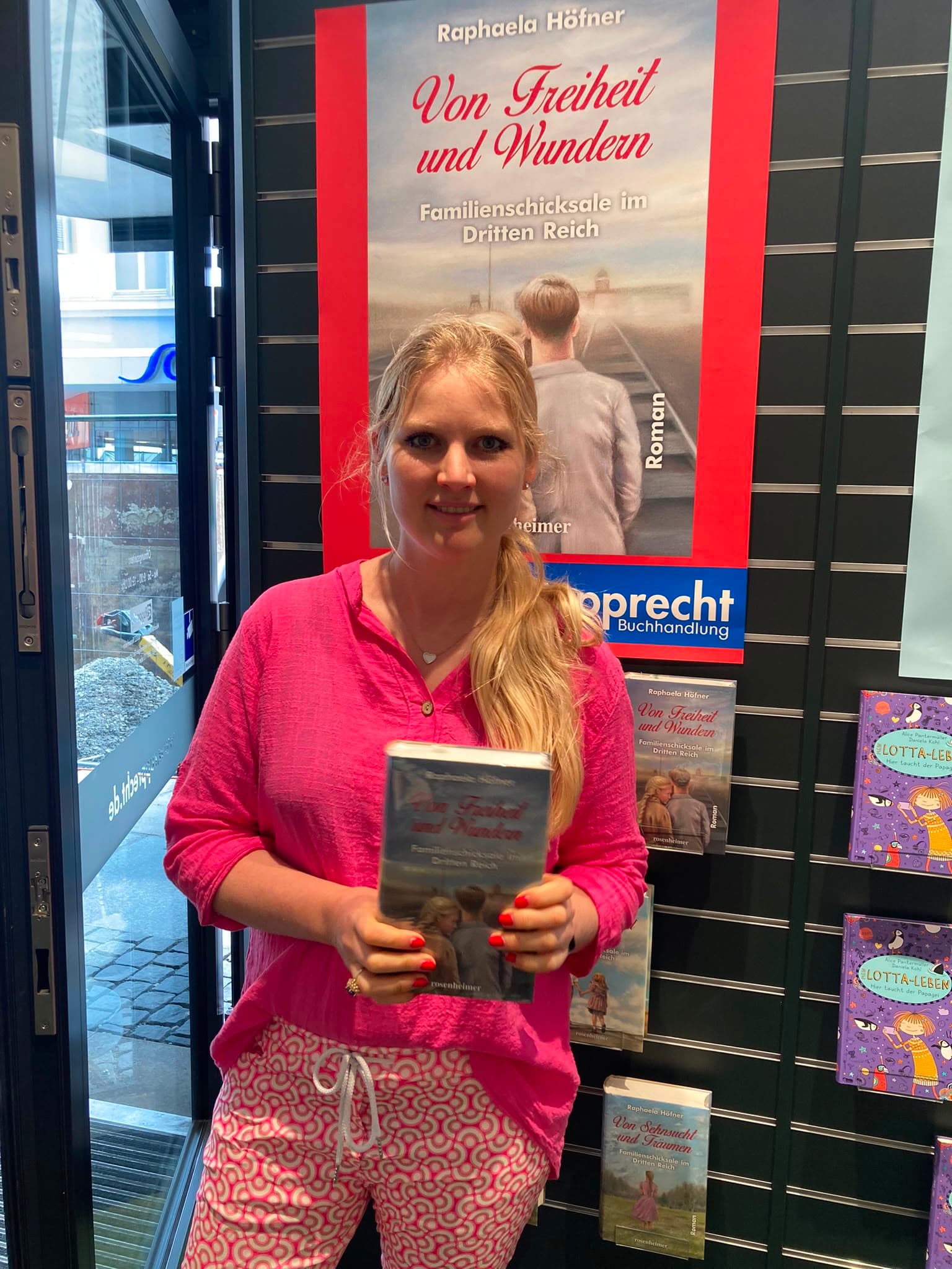 Raphaela Höfner in einer Buchhandlung vor einem Plakat zu „Von Freiheit und Wundern“