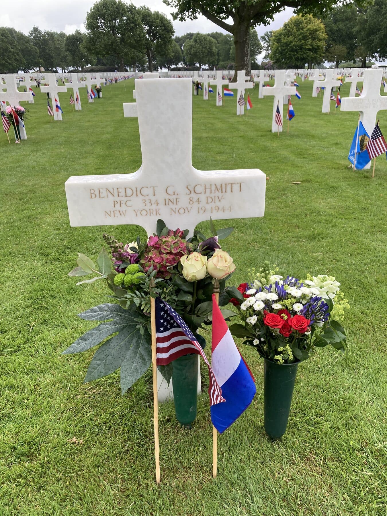 Das Grab von Benedict G. Schmitt auf dem Soldatenfriedhof Margraten, mit Blumen und Fahnen