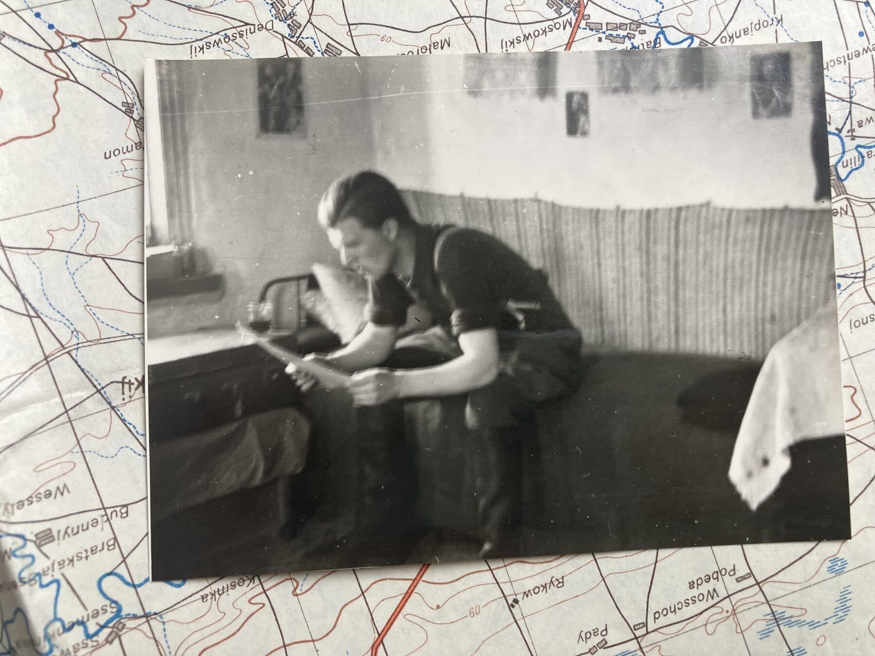 Historische Aufnahme eines Soldaten in einem Quartier, auf einer Landkarte liegend