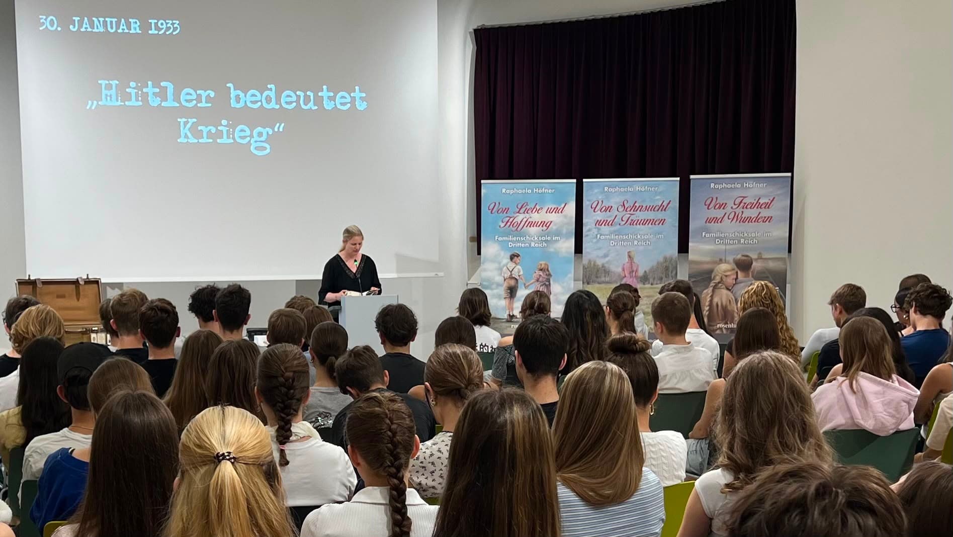 Schullesung vor vollem Saal, auf der Leinwand steht „30. Januar 1933. Hitler bedeutet Krieg“