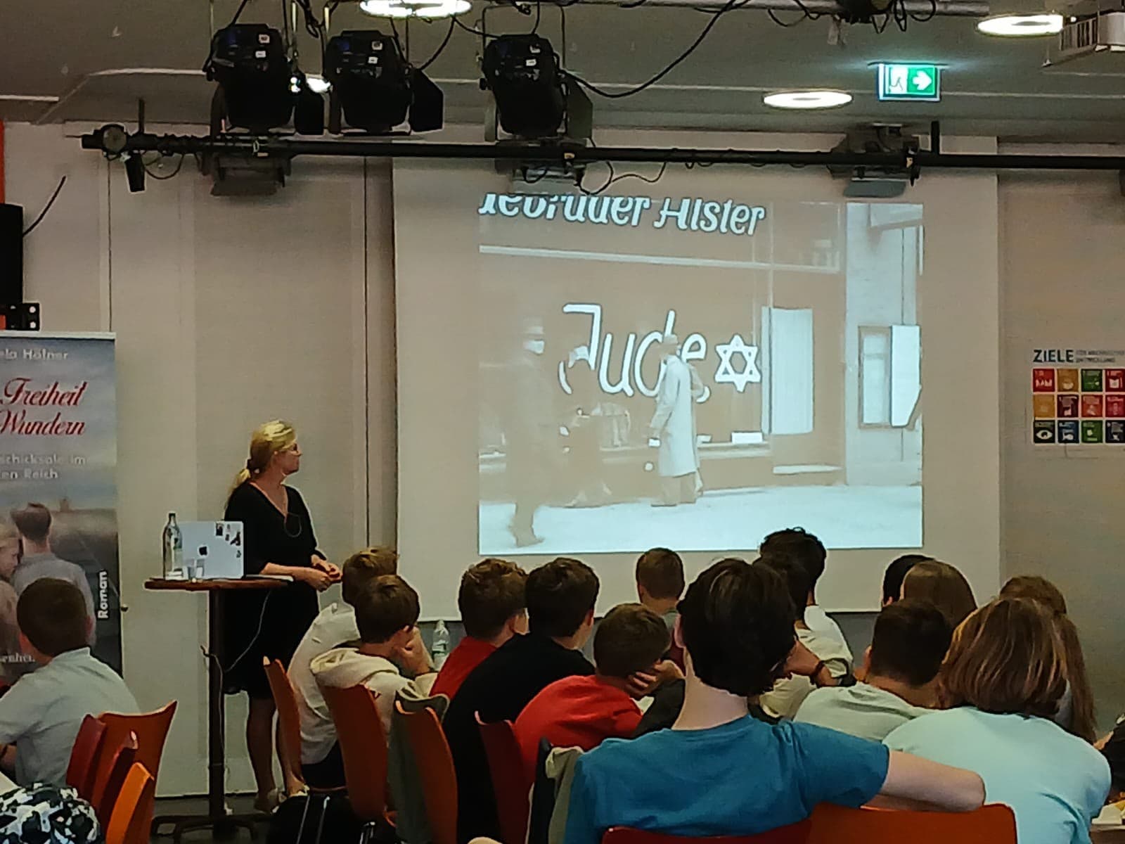 Raphaela Höfner vor einer Projektion eines mit „Jude“ beschmierten Schaufensters