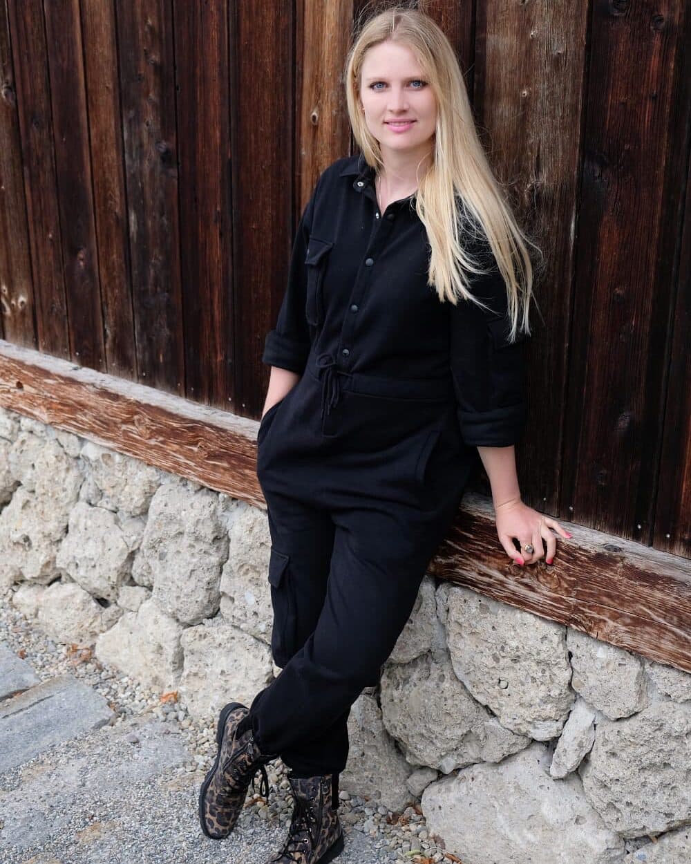 Raphaela Höfner an einer Bruchsteinmauer vor einer Holzwand
