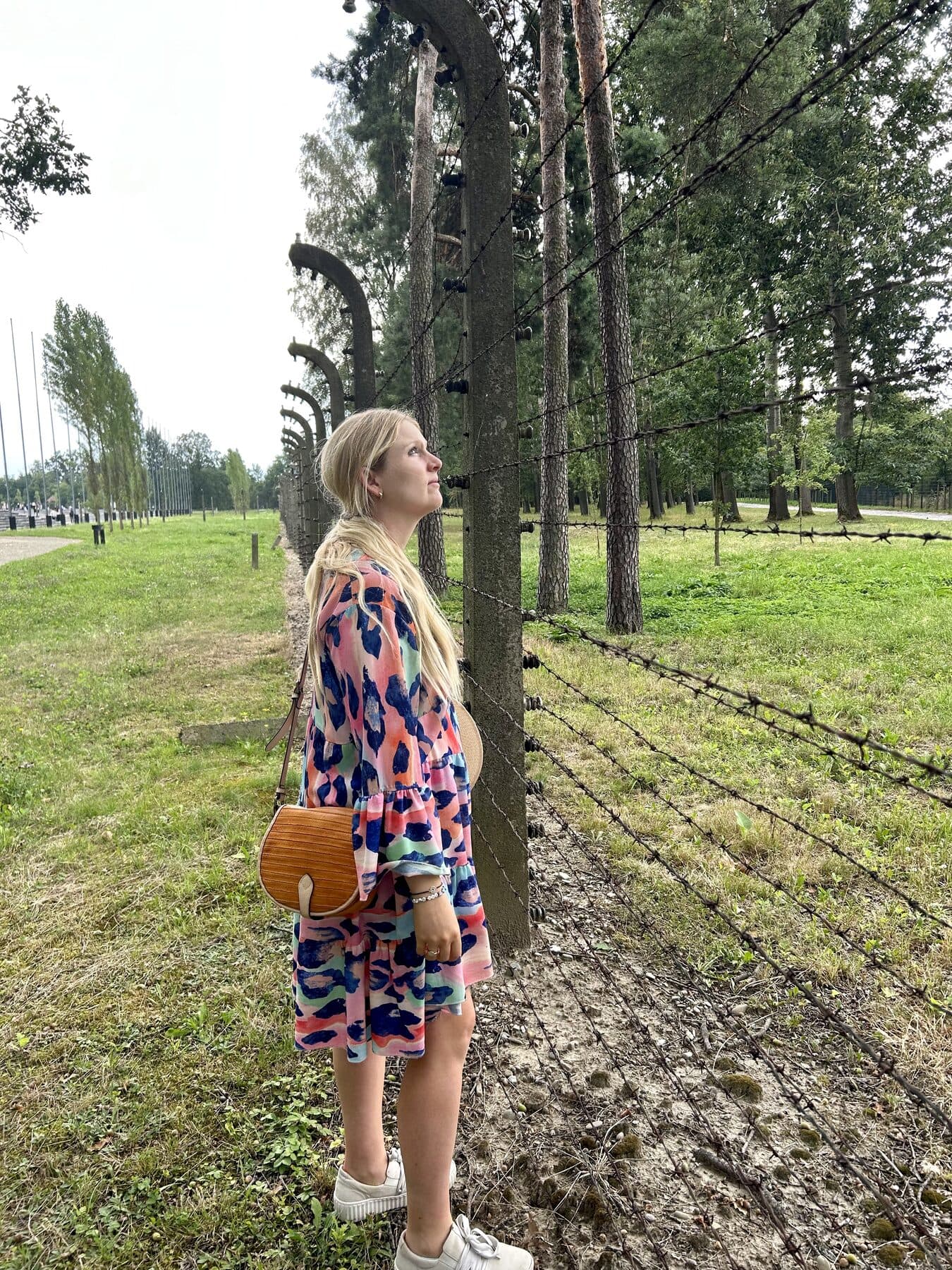 Raphaela Höfner am Stacheldrahtzaun des ehemaligen Lagers Birkenau
