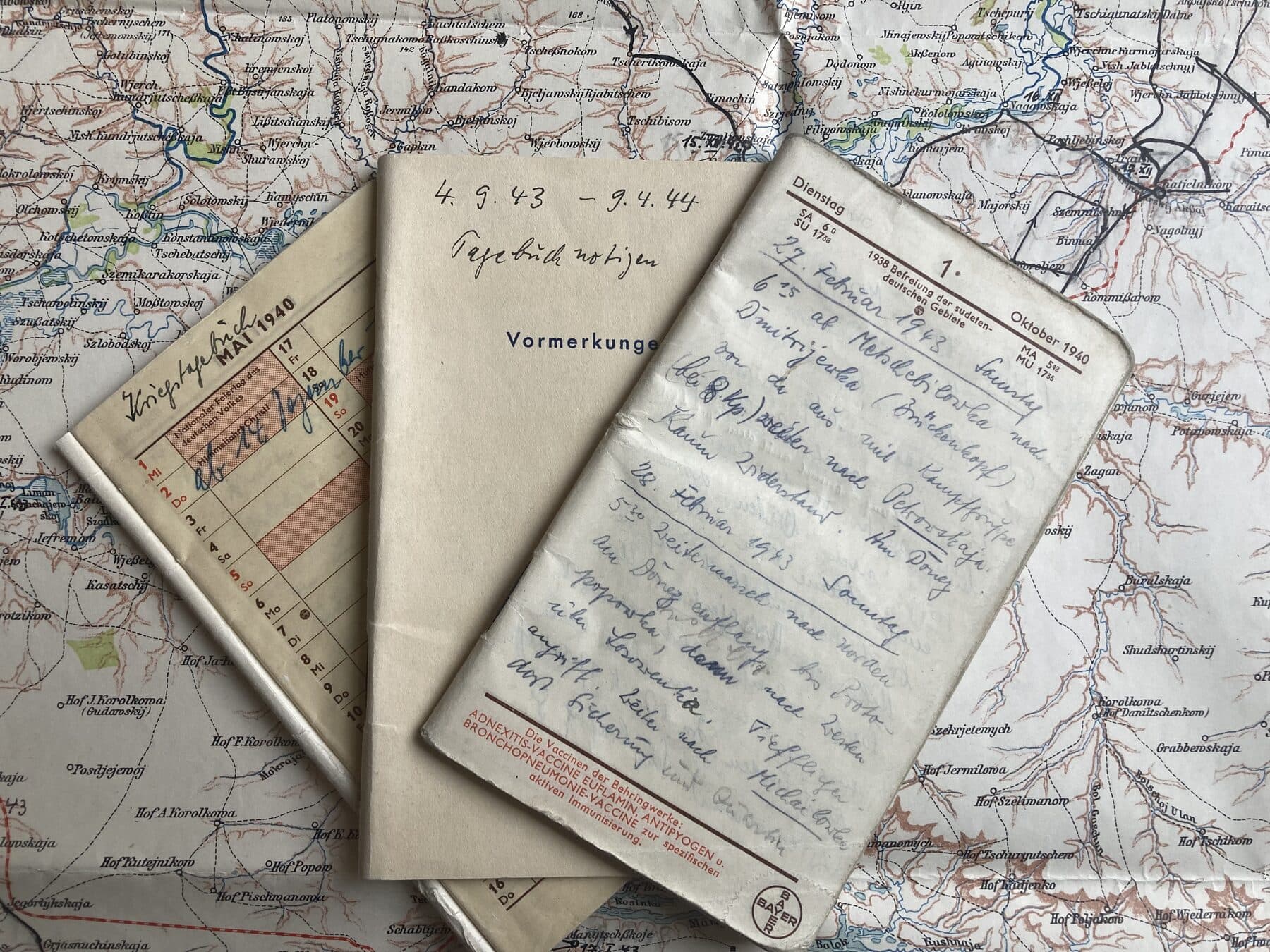 Drei Kriegstagebücher von 1943 und 1944, aufgeschlagen auf einer alten Landkarte