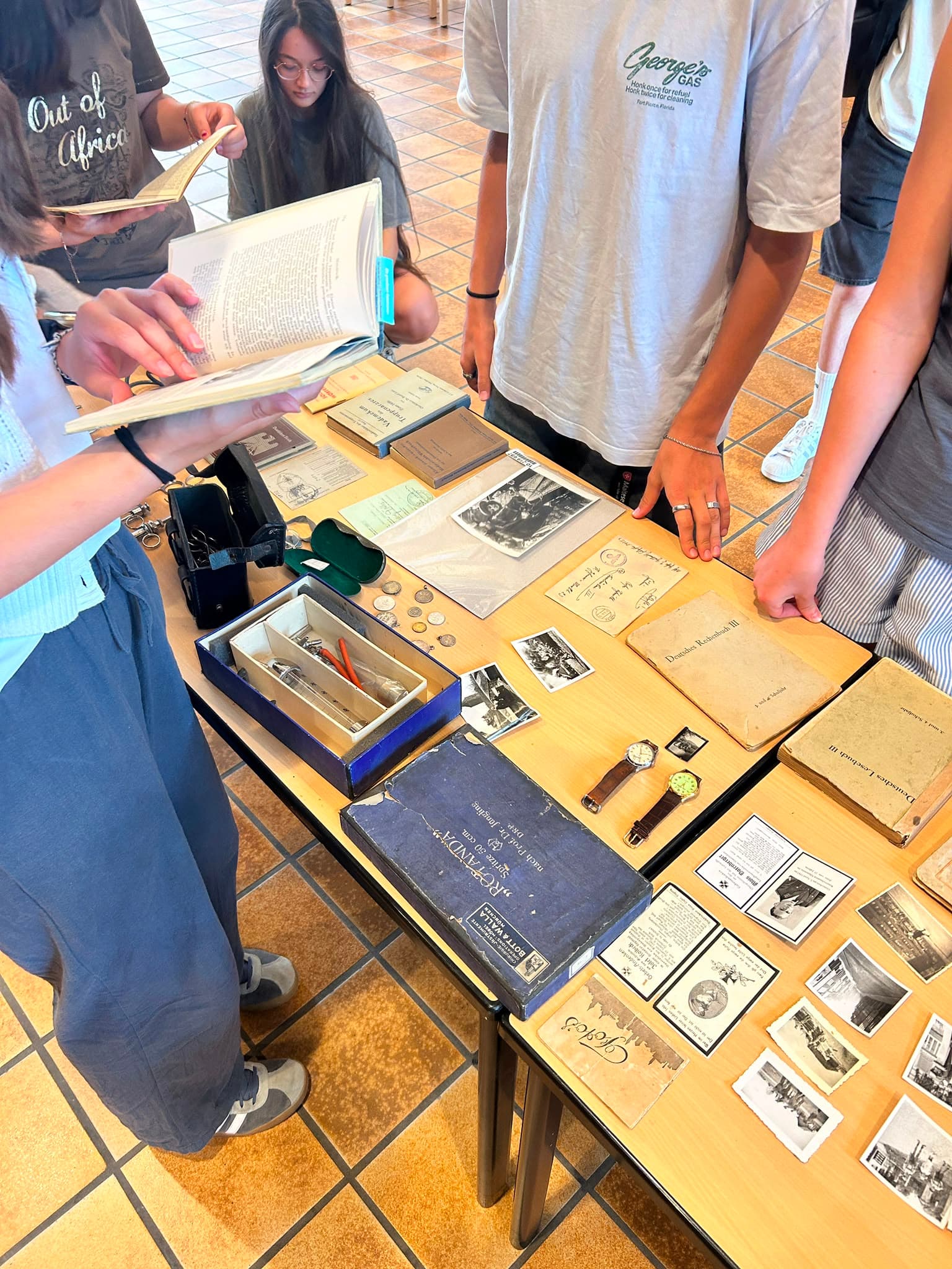 Schülerinnen und Schüler betrachten historische Objekte und Fotografien auf einem Tisch